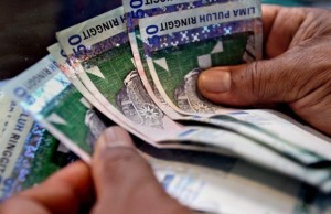 A money changer counts Malaysian ringgit